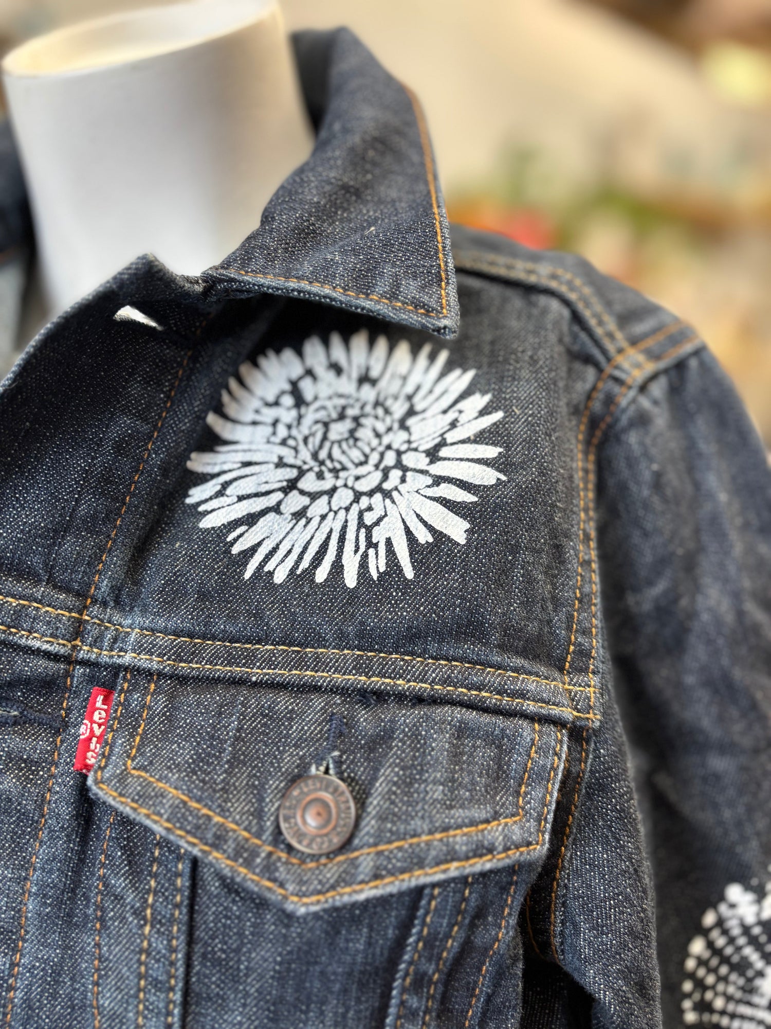 a hand screen printed giant white flower on the back of a grey womens suit jacket